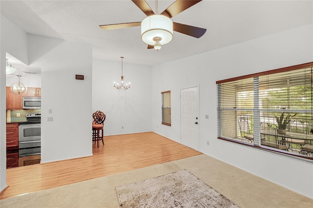 interior space with lofted ceiling, wood finished floors, and ceiling fan with notable chandelier