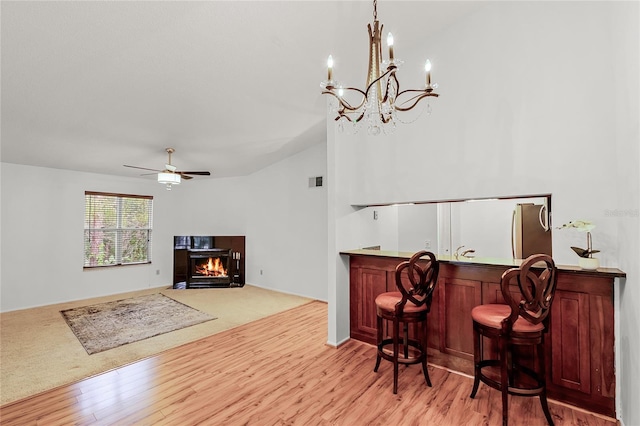 interior space with light wood-style flooring, visible vents, a ceiling fan, a lit fireplace, and a dry bar