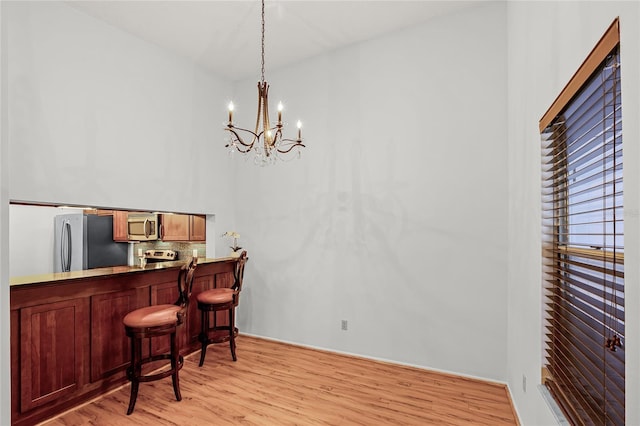 bar with appliances with stainless steel finishes, light wood-type flooring, hanging light fixtures, and decorative backsplash