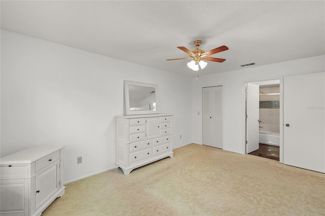 unfurnished bedroom with light colored carpet, connected bathroom, visible vents, and a textured ceiling