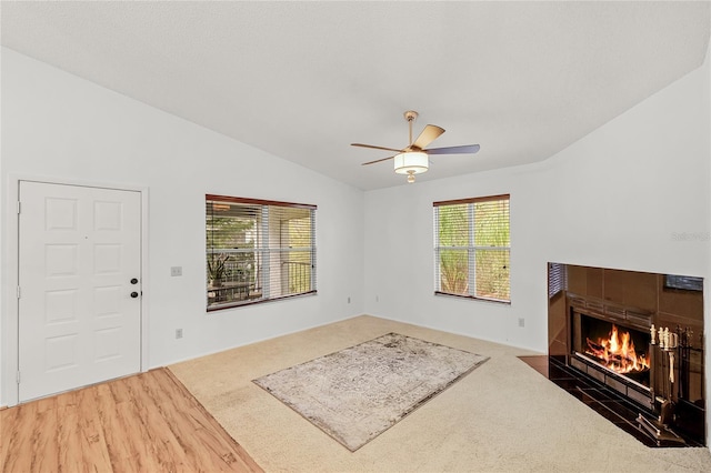 living area with a fireplace, vaulted ceiling, a ceiling fan, and wood finished floors