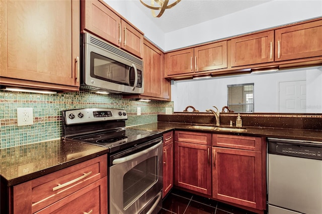 kitchen featuring dark stone counters, stainless steel appliances, tasteful backsplash, and a sink