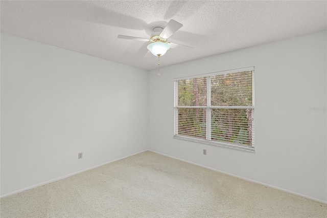 carpeted spare room with ceiling fan, baseboards, and a textured ceiling