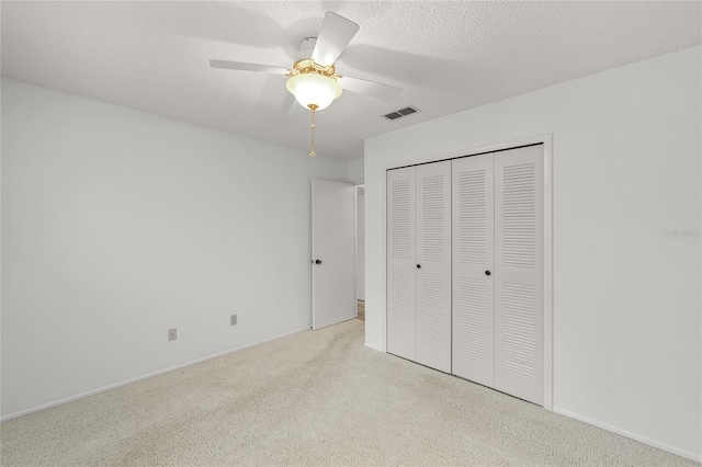 unfurnished bedroom featuring carpet, a closet, visible vents, a ceiling fan, and a textured ceiling