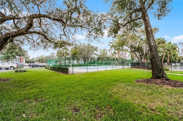 exterior space featuring a tennis court, fence, and a yard