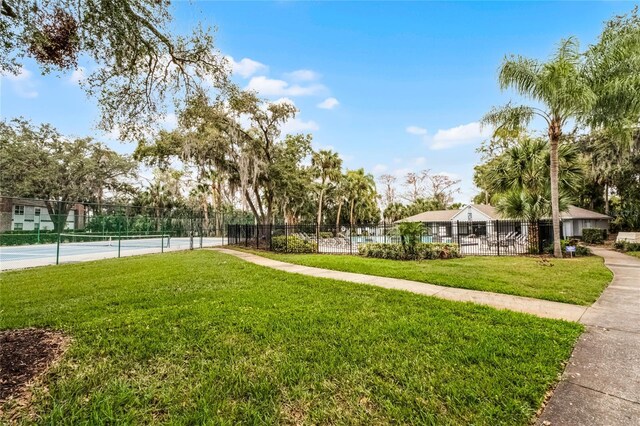 surrounding community featuring a tennis court, a lawn, and fence