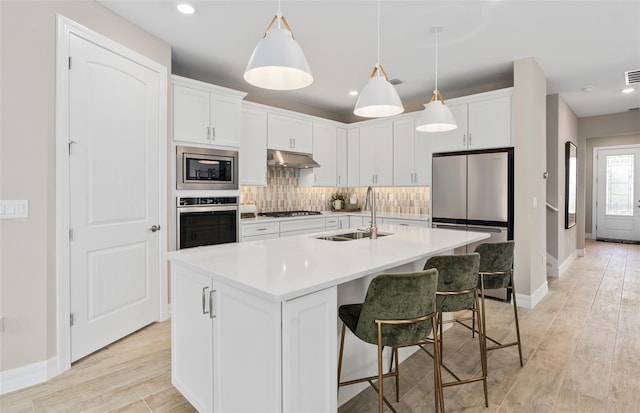 kitchen featuring white cabinetry, sink, a center island with sink, and appliances with stainless steel finishes