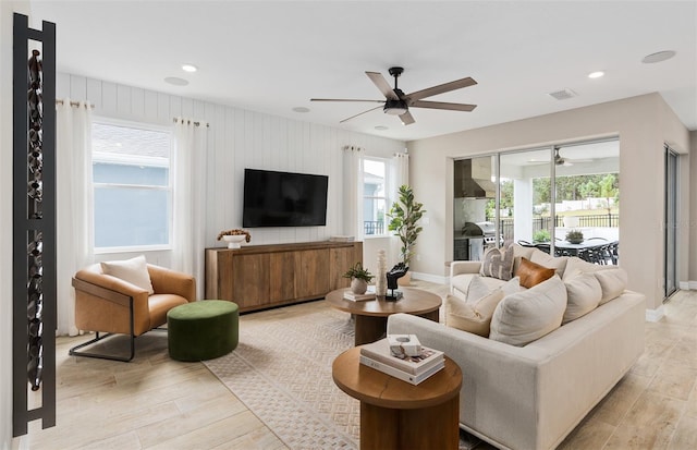 living room with a wealth of natural light, light hardwood / wood-style flooring, and ceiling fan