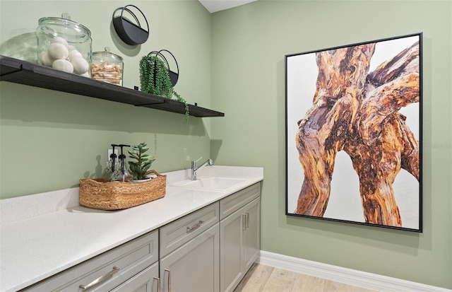 bar featuring gray cabinets, sink, and light hardwood / wood-style floors