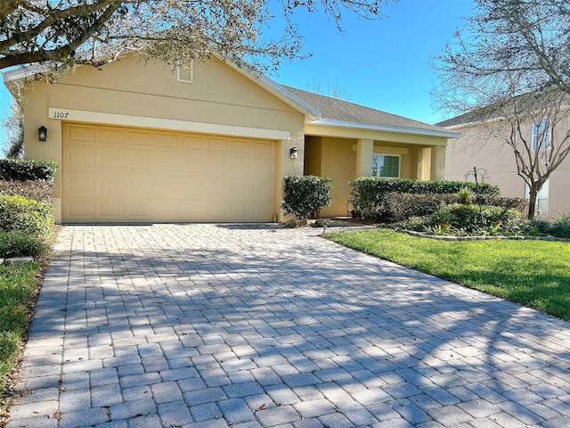 single story home featuring an attached garage, a front lawn, decorative driveway, and stucco siding