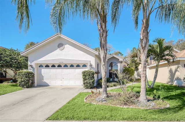 single story home featuring an attached garage, driveway, a front lawn, and stucco siding