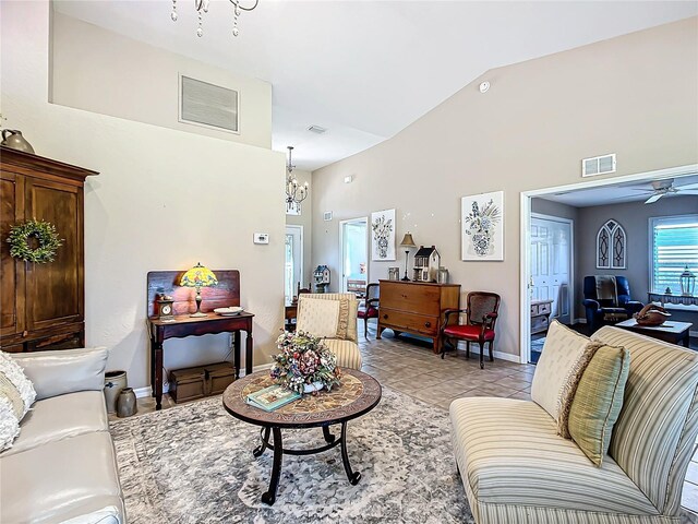 living room with ceiling fan with notable chandelier, light tile patterned floors, and vaulted ceiling