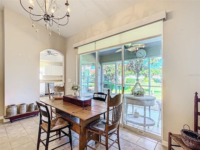 tiled dining space featuring ceiling fan with notable chandelier and lofted ceiling