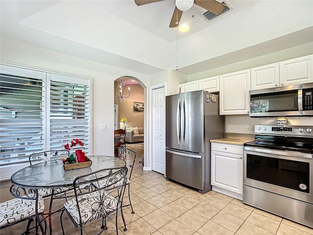 kitchen featuring light tile patterned floors, white cabinetry, a tray ceiling, ceiling fan, and stainless steel appliances