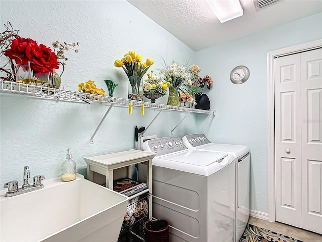washroom featuring sink, independent washer and dryer, a textured ceiling, and tile patterned floors
