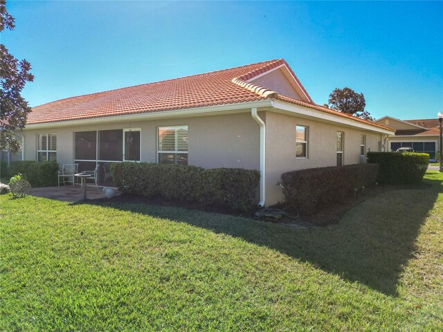 view of property exterior featuring a lawn and a patio area