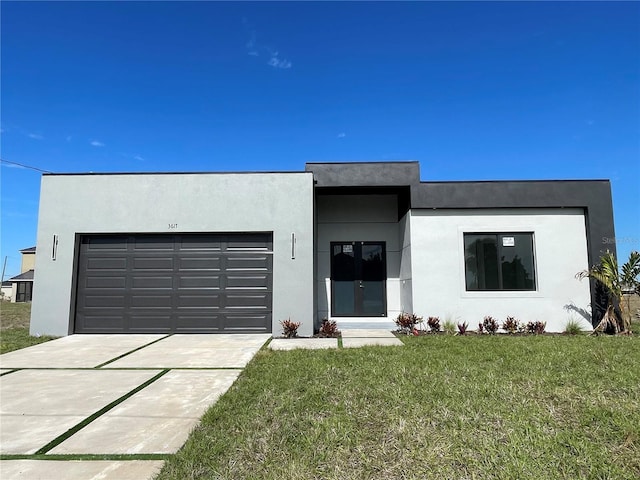 view of front of home with an attached garage, driveway, a front yard, and stucco siding