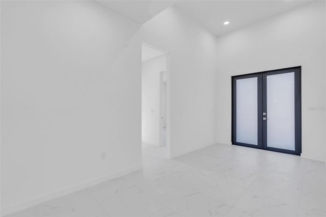 spare room featuring recessed lighting, marble finish floor, baseboards, and french doors