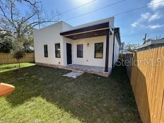 2604 E 11th Ave, Tampa, FL 33605 - back of property featuring a fenced backyard, stucco siding, and a lawn