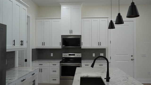 2604 E 11th Ave, Tampa, FL 33605 - kitchen with light stone counters, backsplash, pendant lighting, appliances with stainless steel finishes, and white cabinets