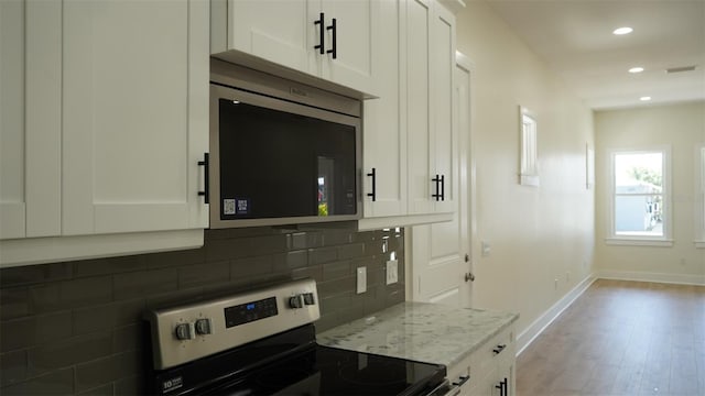 2604 E 11th Ave, Tampa, FL 33605 - kitchen with decorative backsplash, white cabinets, stainless steel appliances, and light stone counters