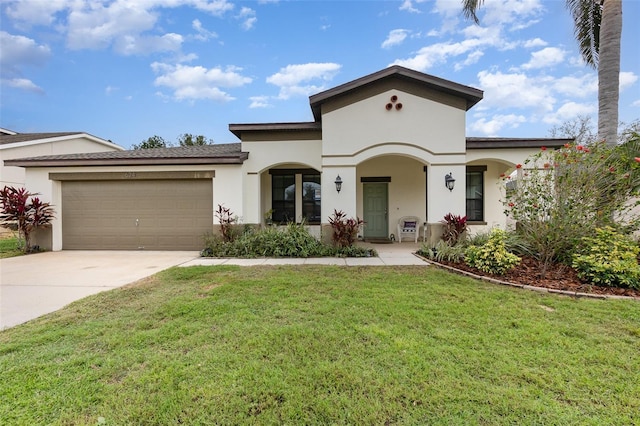 mediterranean / spanish home featuring a garage, a front lawn, concrete driveway, and stucco siding