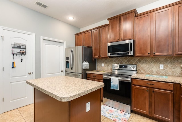 kitchen featuring light tile patterned floors, stainless steel appliances, light countertops, visible vents, and a kitchen island