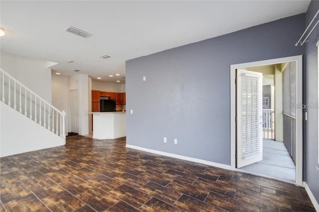 unfurnished living room with stairs, dark wood finished floors, visible vents, and baseboards