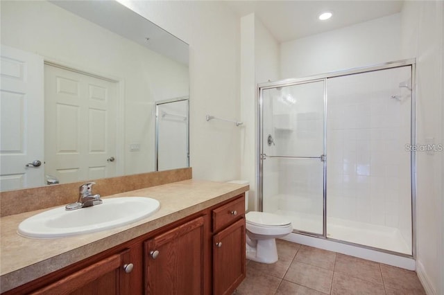 bathroom with vanity, a shower stall, toilet, and tile patterned floors