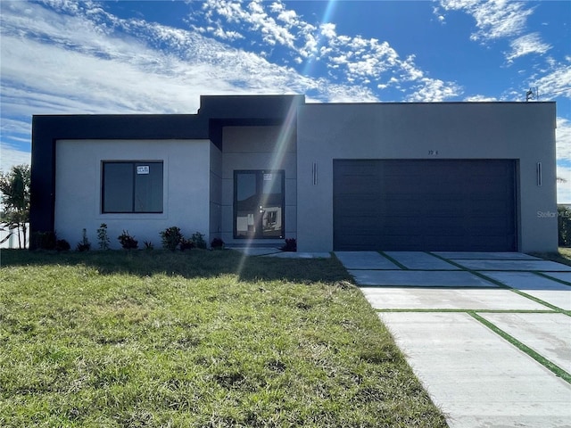 contemporary home with an attached garage, driveway, a front yard, and stucco siding