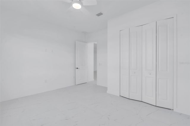 3924 NW 38th St, Cape Coral, FL 33993 - unfurnished bedroom featuring light marble finish floors, a closet, and ceiling fan