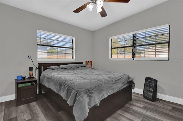 bedroom featuring multiple windows, dark hardwood / wood-style floors, and ceiling fan