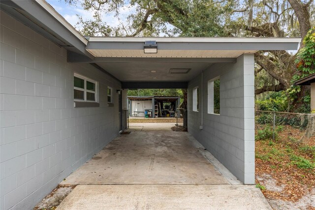 view of car parking featuring a carport, fence, and driveway