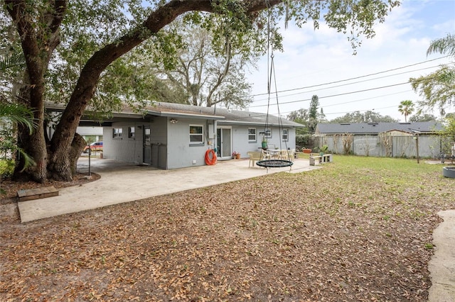 back of property featuring a fire pit, fence, a lawn, and a patio