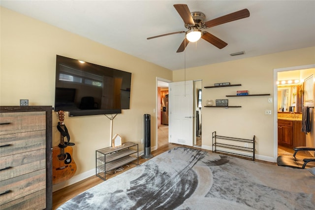 interior space with a ceiling fan, visible vents, baseboards, and wood finished floors