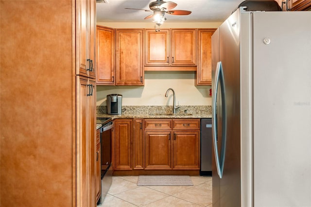 kitchen featuring brown cabinetry, range, a sink, and freestanding refrigerator