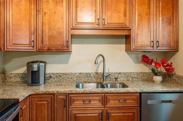 kitchen featuring light stone countertops, appliances with stainless steel finishes, brown cabinetry, and a sink