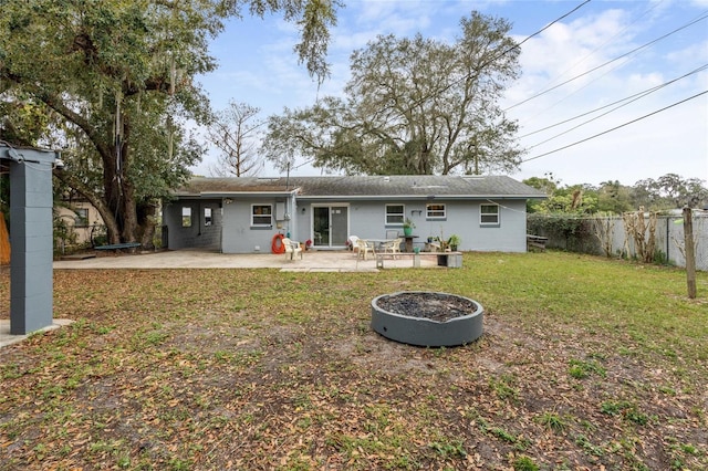 rear view of house featuring a patio area, fence, a fire pit, and a lawn