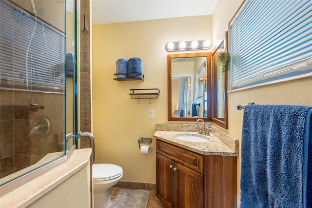 full bathroom with toilet, a tile shower, vanity, tile patterned flooring, and baseboards