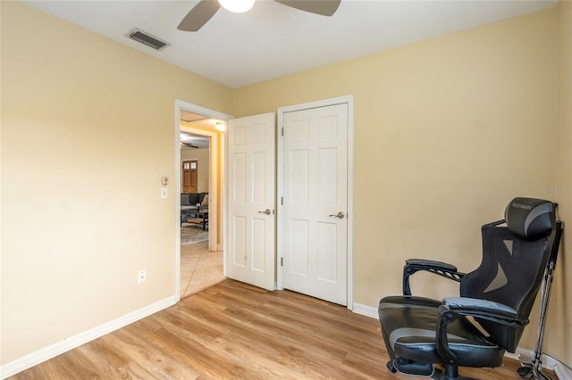 sitting room featuring a ceiling fan, light wood-style flooring, visible vents, and baseboards