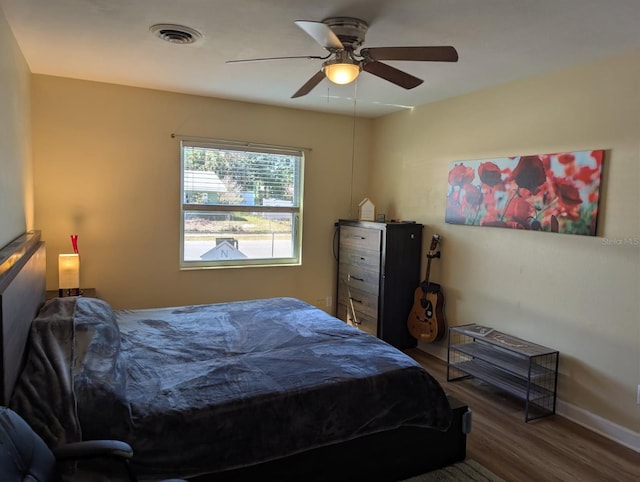 bedroom with baseboards, visible vents, wood finished floors, and ceiling fan
