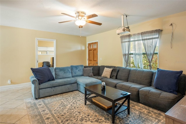 living area featuring light tile patterned floors, a ceiling fan, and baseboards