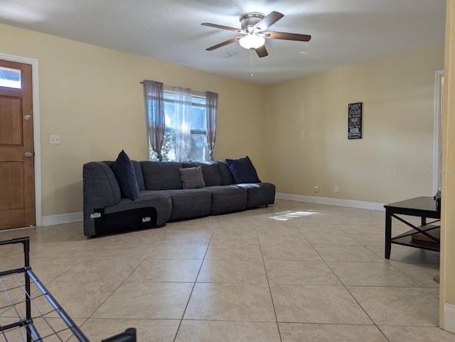 living area featuring light tile patterned flooring, ceiling fan, and baseboards