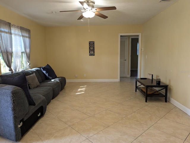 living room featuring light tile patterned floors, ceiling fan, visible vents, and baseboards