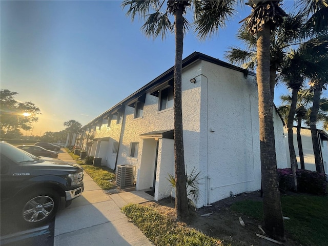 view of side of home with stucco siding and central AC