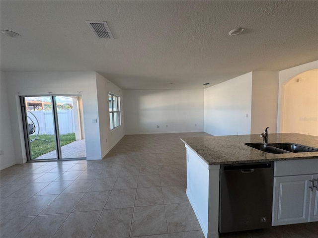 kitchen featuring light tile patterned floors, sink, stone counters, stainless steel dishwasher, and white cabinets