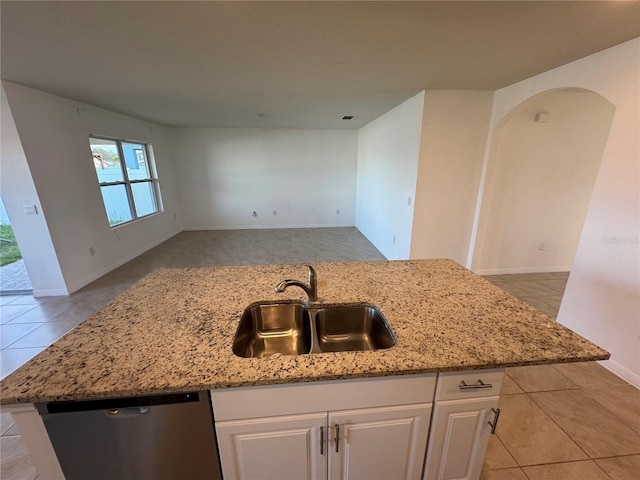 kitchen with an island with sink, stainless steel dishwasher, sink, and white cabinetry