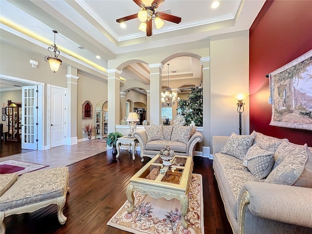 living room featuring dark hardwood / wood-style flooring, ornamental molding, ornate columns, and a raised ceiling