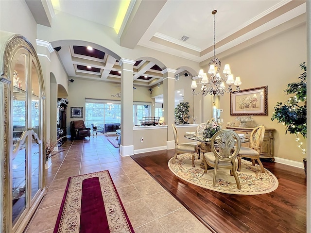 dining space featuring hardwood / wood-style flooring, beam ceiling, a notable chandelier, ornate columns, and coffered ceiling