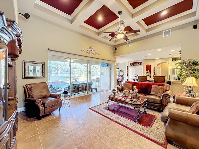 tiled living room with coffered ceiling, ornamental molding, a towering ceiling, and ceiling fan